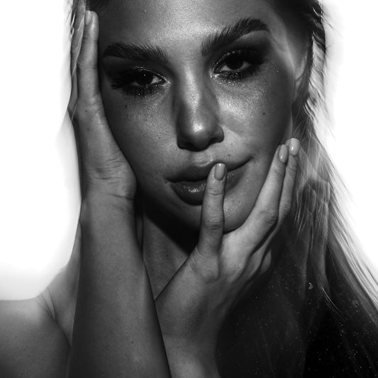 A black and white photo of a woman with her hands on her face
