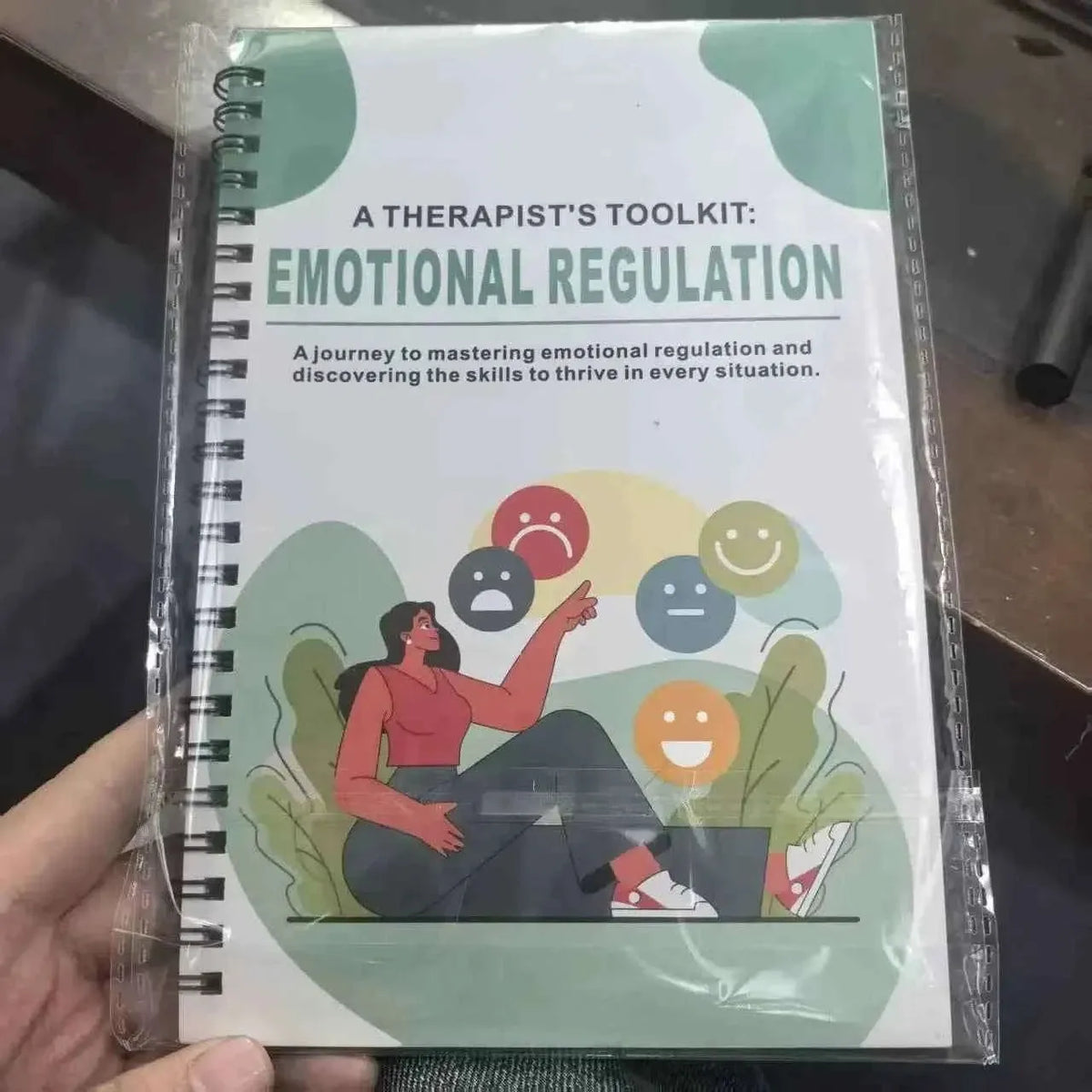 Spiral-bound emotional regulation workbook in plastic wrap, front cover illustration visible.