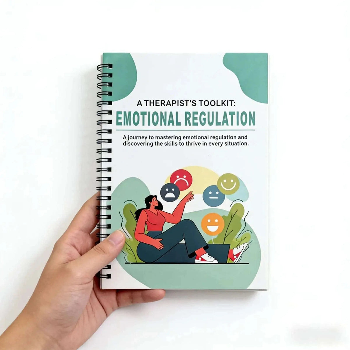 Hand holding spiral-bound emotional regulation workbook with illustrated front cover.