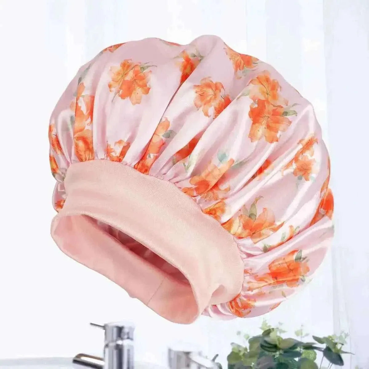 Satin hair bonnet, pink with orange floral print and wide ruffled brim, folded for display