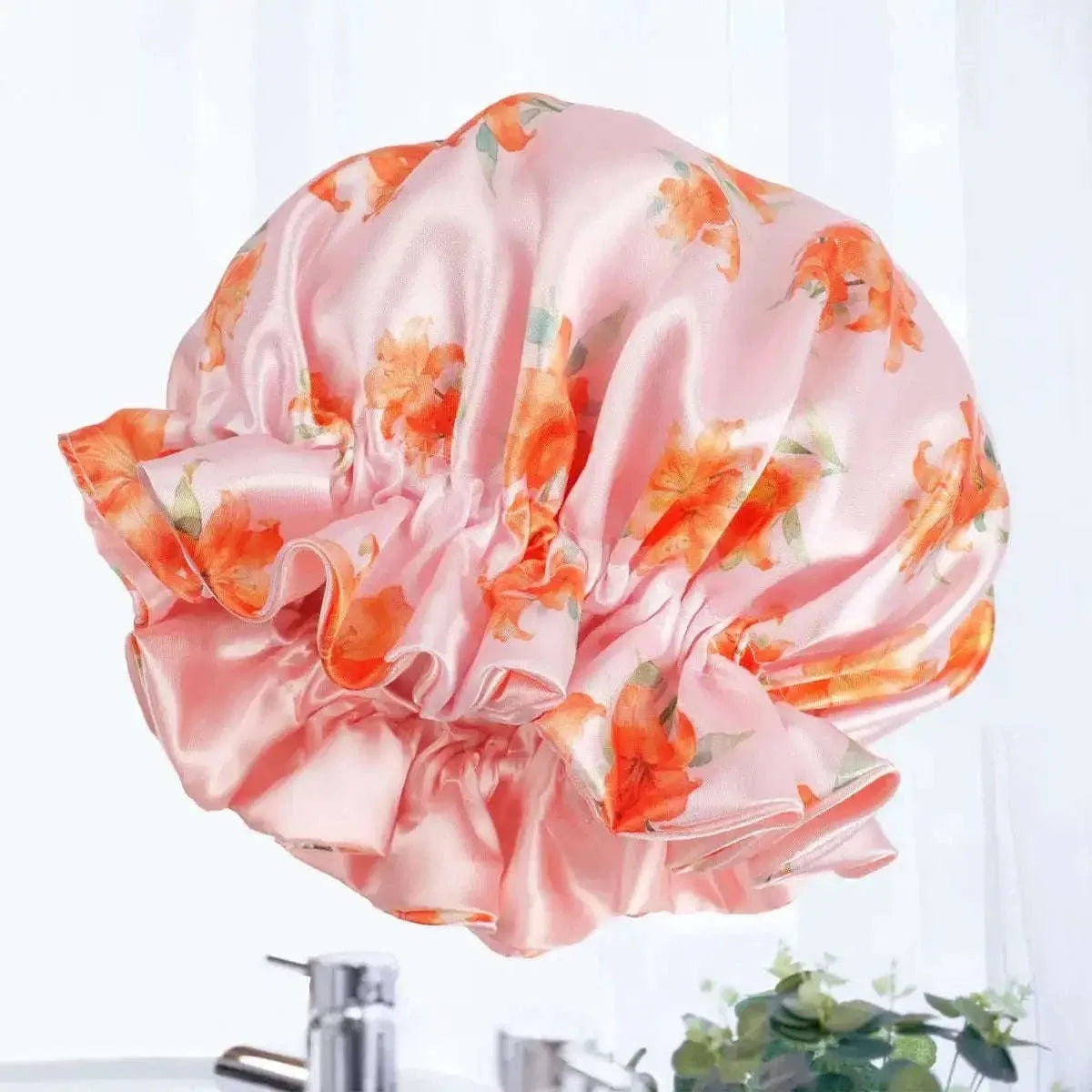 Satin hair bonnet in pink with orange floral print, gathered ruffles and curved crown shape