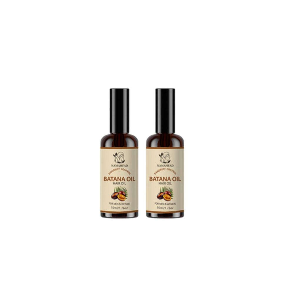 Hand holding a bottle of Namahfad Batana Hair Oil against a blurred natural background.  